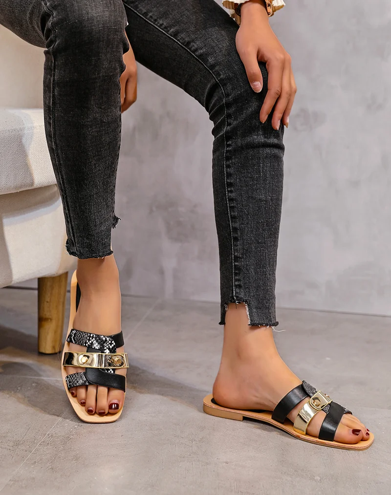 Mules plates noires à brides entremêlées et détails python et dorés